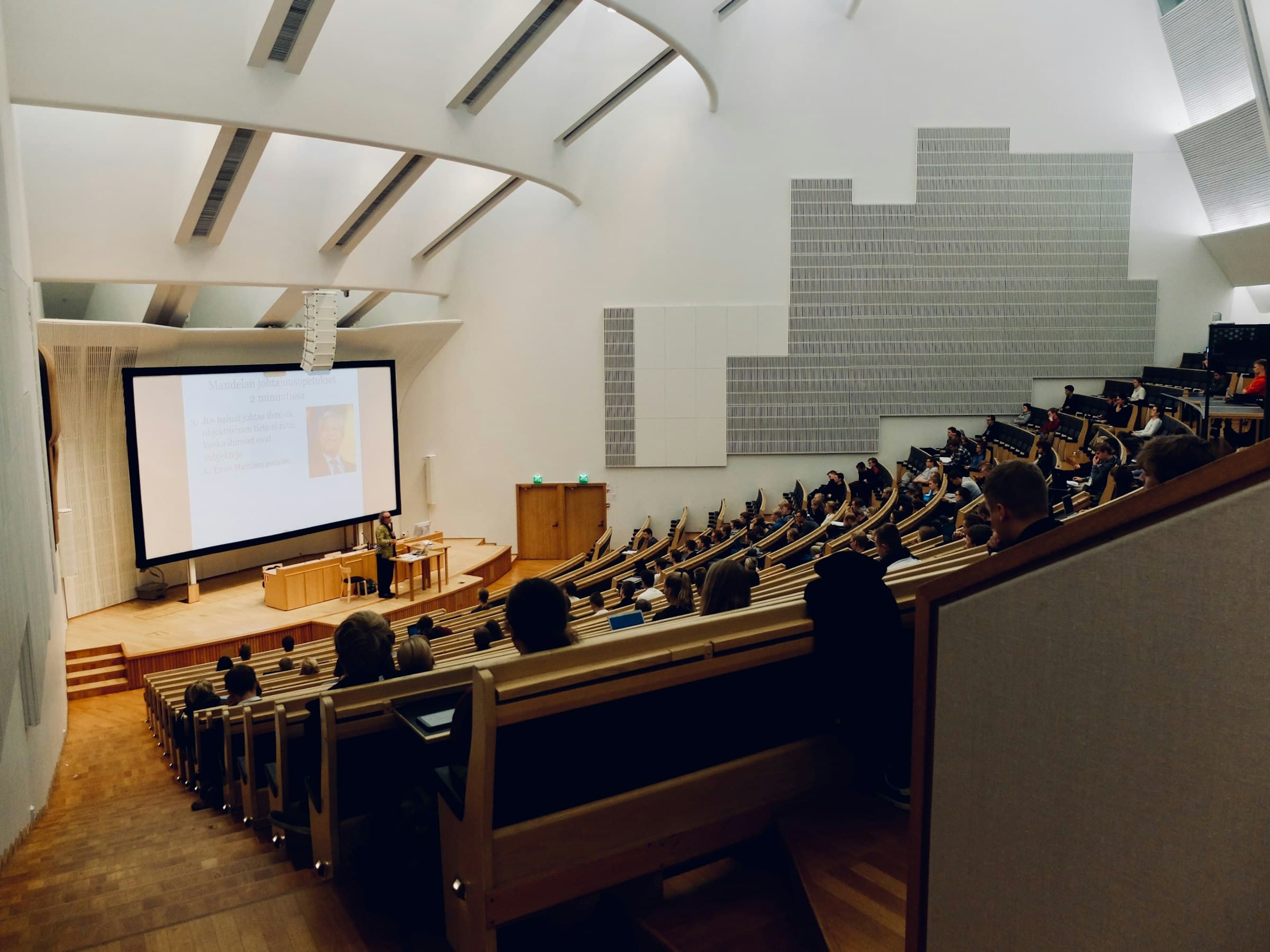 Collegezaal met werktafels en een projectiescherm